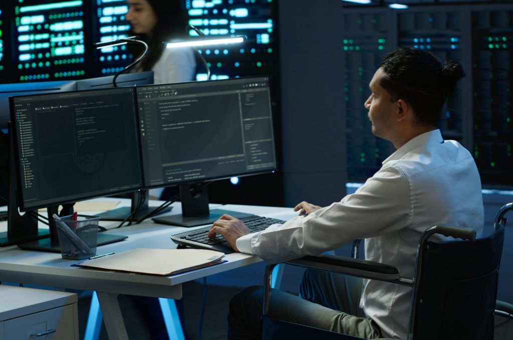 Person with disability in inclusive high tech server room facility ensuring data remains shielded from threats. Wheelchair user protecting data center hardware equipment, camera A